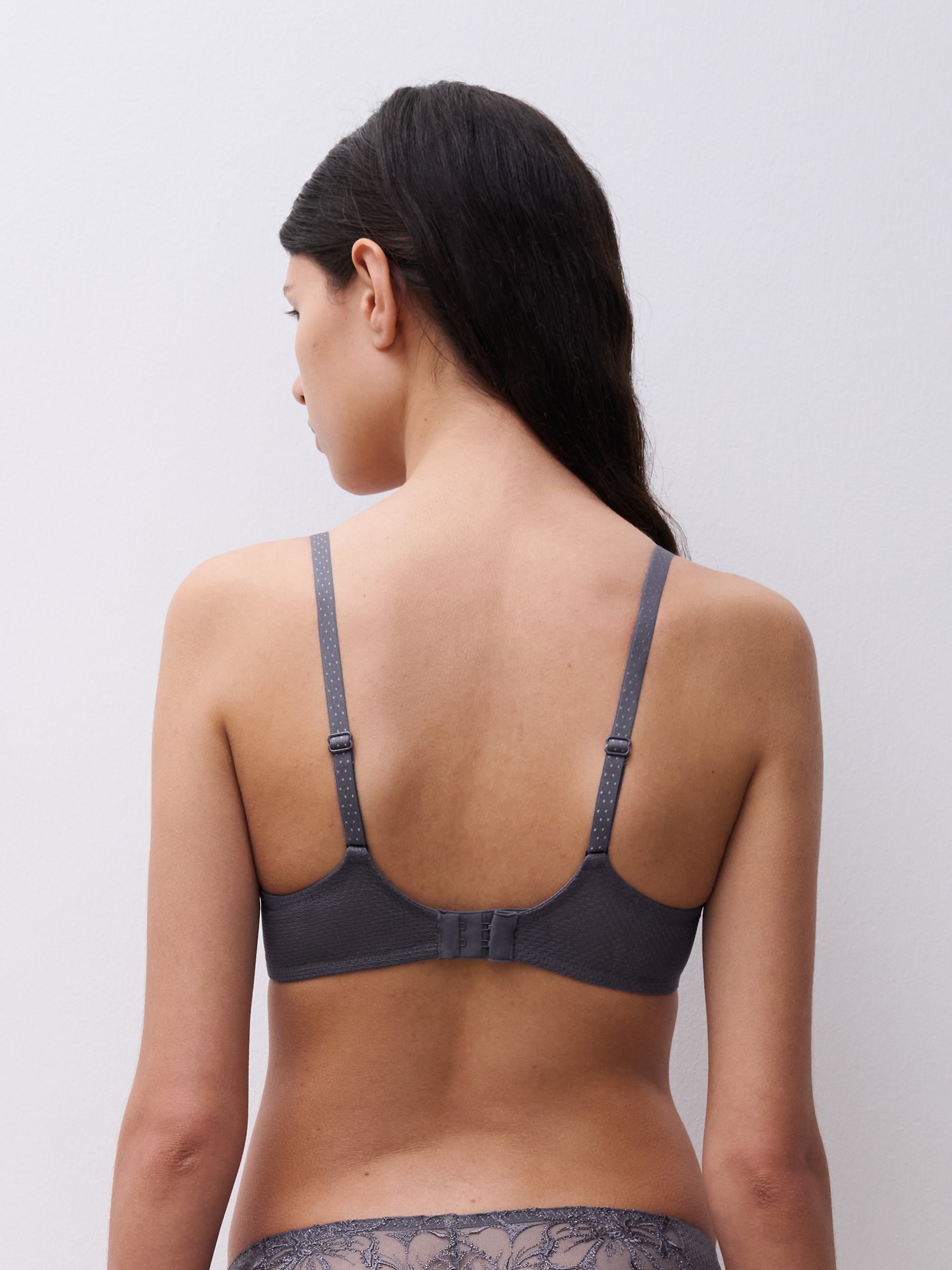 Back view of the Chantelle Fleurs Unlined Bra in Stardust Grey, featuring dotted adjustable straps and a smooth mesh band with a hook-and-eye closure.